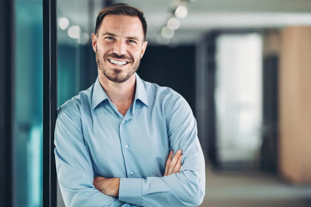Homme souriant adossé contre un mur dans un bureau, distributeur agréé experts en solution de gestion BTP